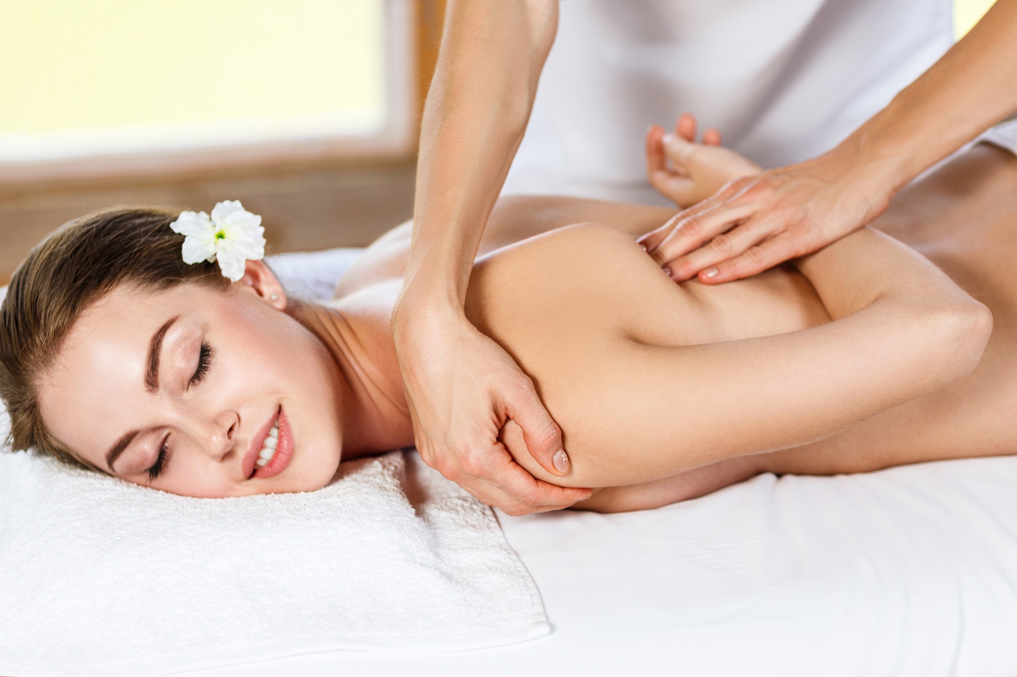 Young beautiful woman lying on massage table and enjoying massage.